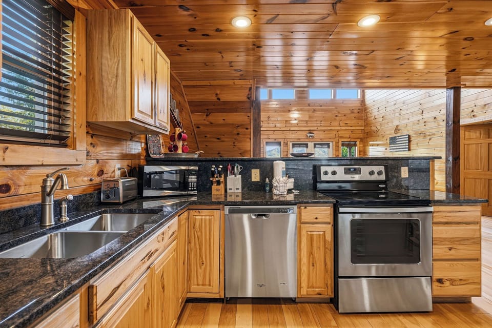 Your fully equipped kitchen features granite counters, stainless steel appliances, and warm wood cabinetry—perfect for preparing home-cooked meals during your mountain getaway.