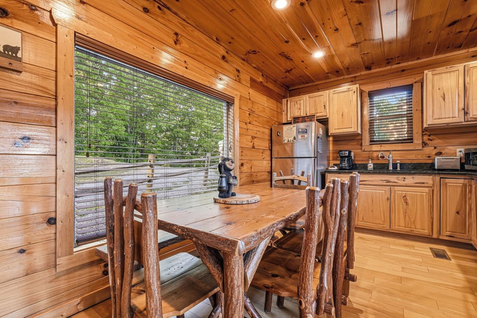 Gather around the handcrafted log table in your fully equipped kitchen, where warm wood tones and forest views create the perfect backdrop for your mountain getaway meals.