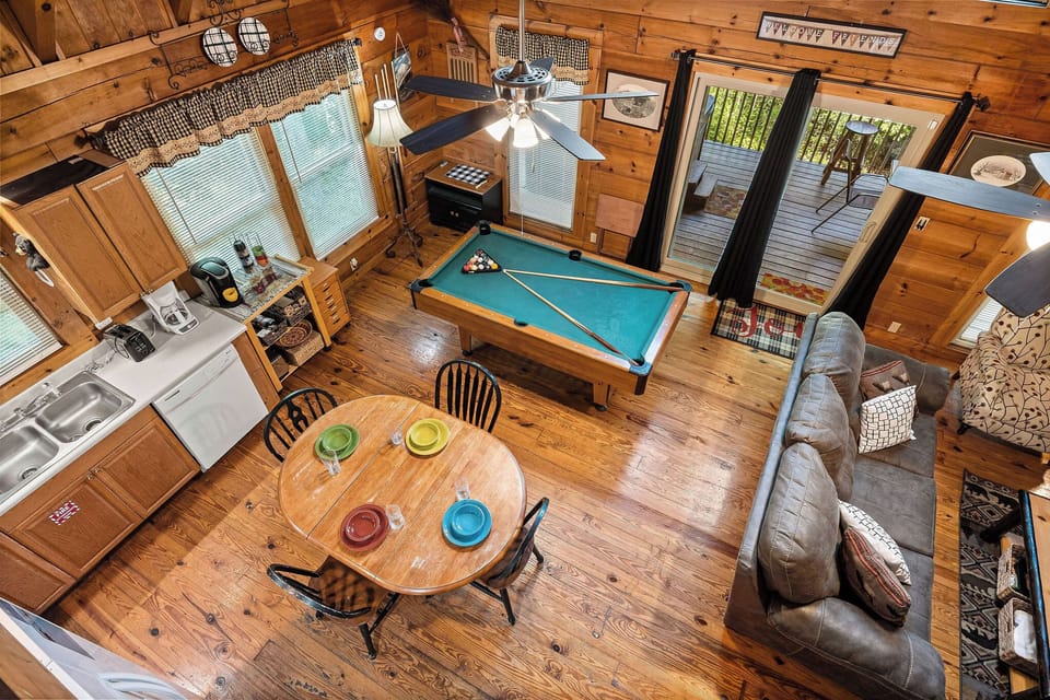 Living room, dining space, and pool table from the loft at Cloud 9, a 1-bedroom cabin rental located in Pigeon Forge