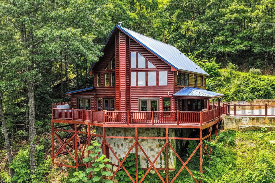A welcoming log cabin nestled among lush forest trees, featuring a spacious wrap-around deck and large windows that invite natural light into your mountain retreat.