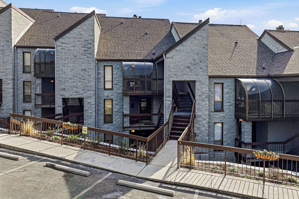 Modern stone property complex featuring distinctive curved glass balconies and contemporary architectural design in a well-maintained residential setting.