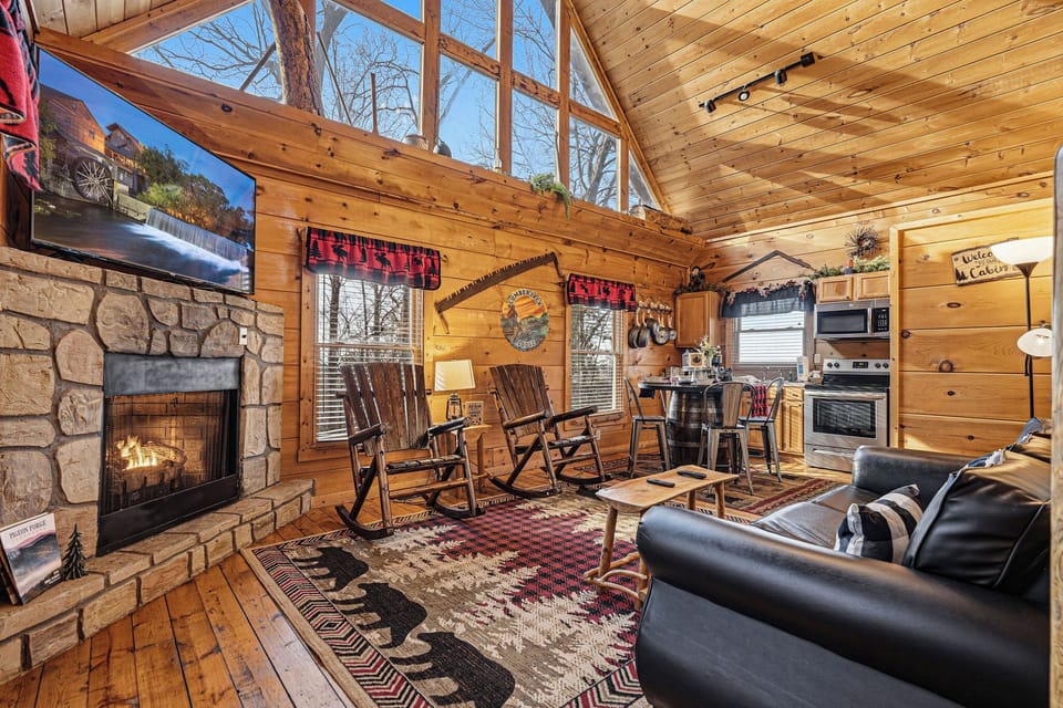 Cozy up in your rustic cabin retreat, where crackling fireplace warmth meets modern comfort beneath soaring wood-beam ceilings.
