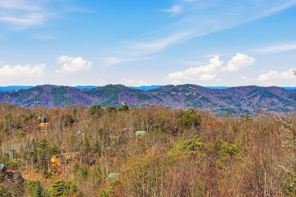 Rolling mountains create a stunning backdrop across forested hills and scattered homes in this peaceful rural setting.