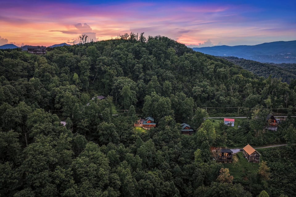 Nestled among lush forested mountains, this property captures the essence of a peaceful mountain retreat, with stunning evening skies painting the perfect backdrop for relaxation.
