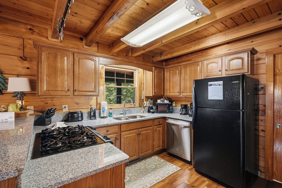 Your rustic cabin kitchen features granite counters, full appliances, and warm wood beams—perfect for cozy mountain meal prep.
