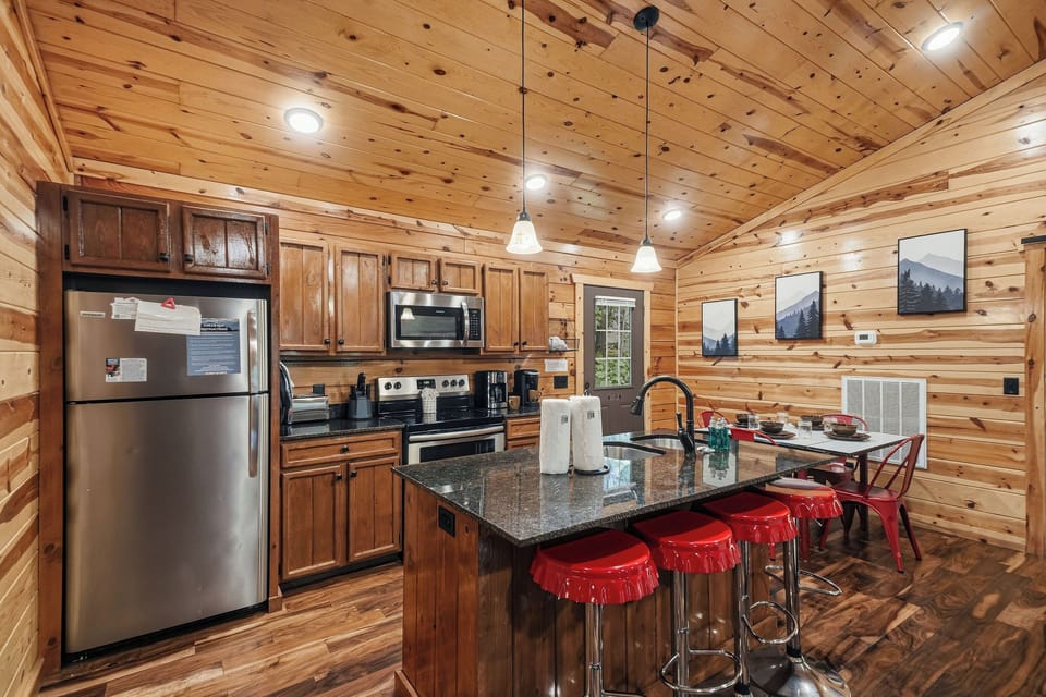Step into your warm, wood-paneled kitchen where granite counters, stainless appliances, and a cozy breakfast island invite you to cook and gather over morning coffee.