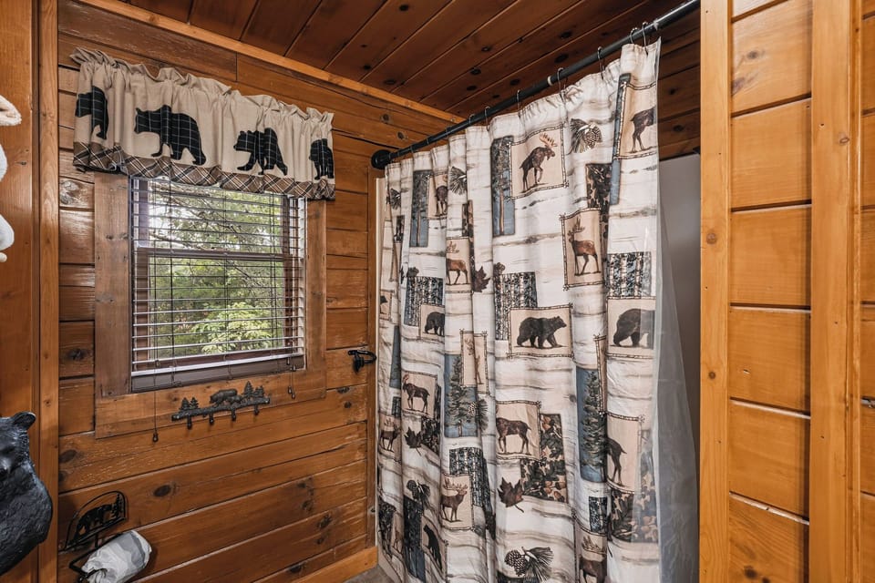 Step into your charming bathroom featuring rustic wood-paneled walls, inviting natural light, and cozy wilderness-themed décor that brings the outdoors in.