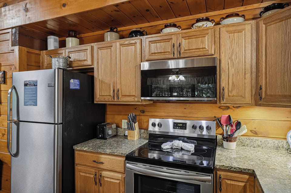 Step into your fully-equipped kitchen, where warm wood cabinets and modern stainless steel appliances make preparing meals a breeze. Everything you need is right at your fingertips in this cozy, rustic space.