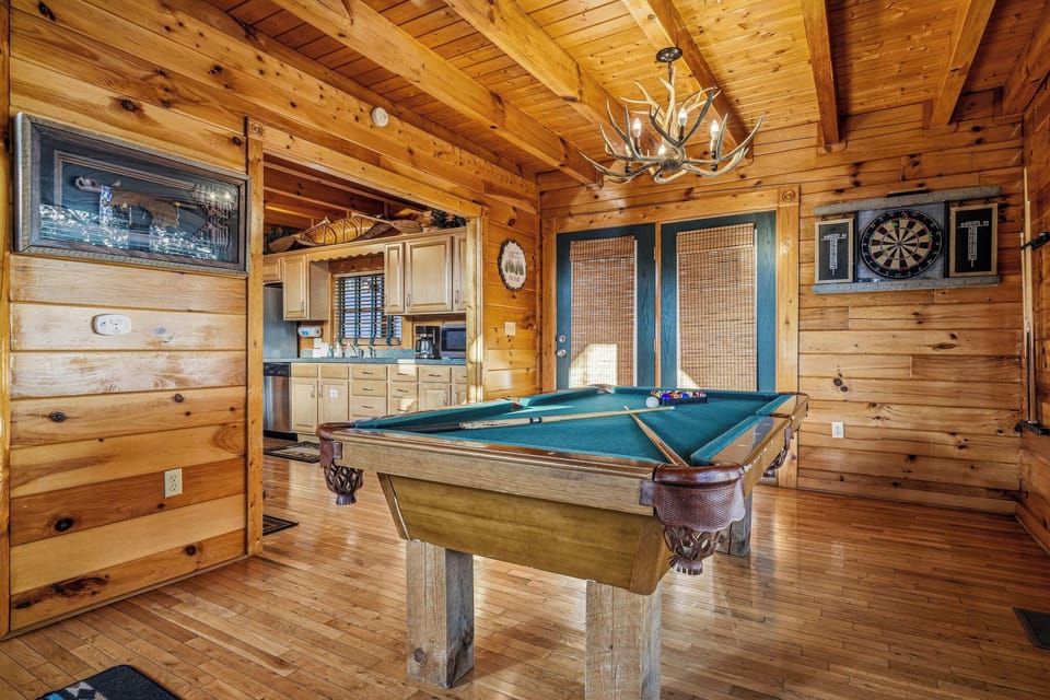 Challenge friends to a game of pool or test your aim at the dartboard in this welcoming game room with soaring wood-beamed ceilings and a rustic antler chandelier overhead.