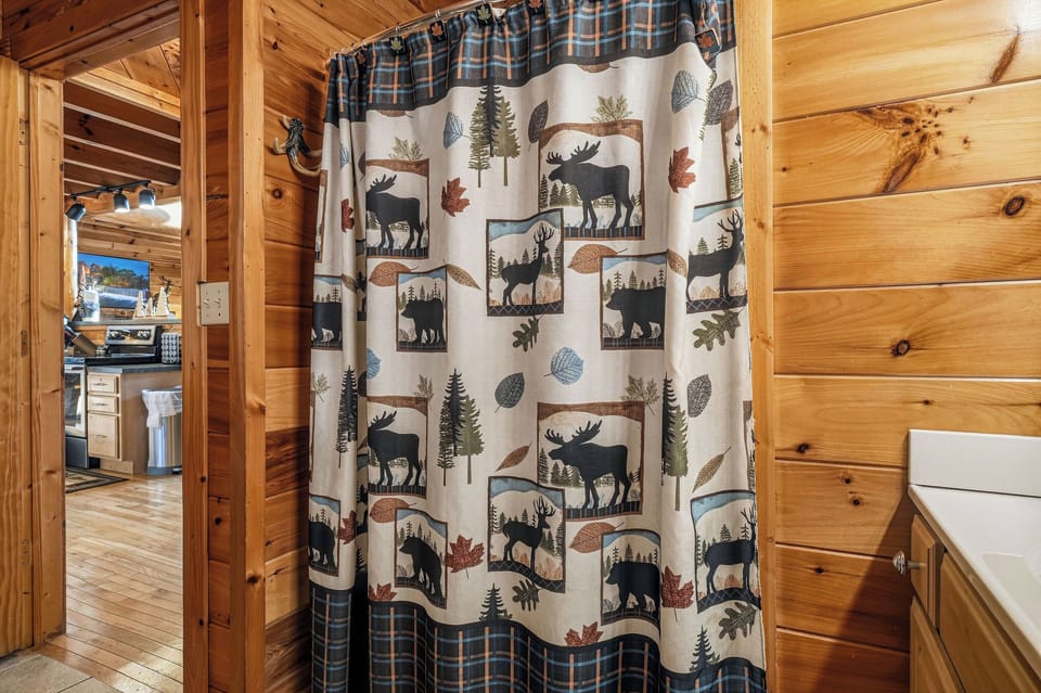 Step into your cozy, rustic-themed bathroom with charming woodland-inspired details. The warm pine walls and nature-themed shower curtain create a cabin-like retreat perfect for unwinding after your adventures.