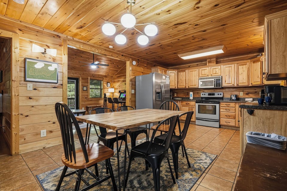 Gather around the cozy dining table in your rustic cabin retreat, where warm wood tones and modern appliances make meal times feel special and inviting.