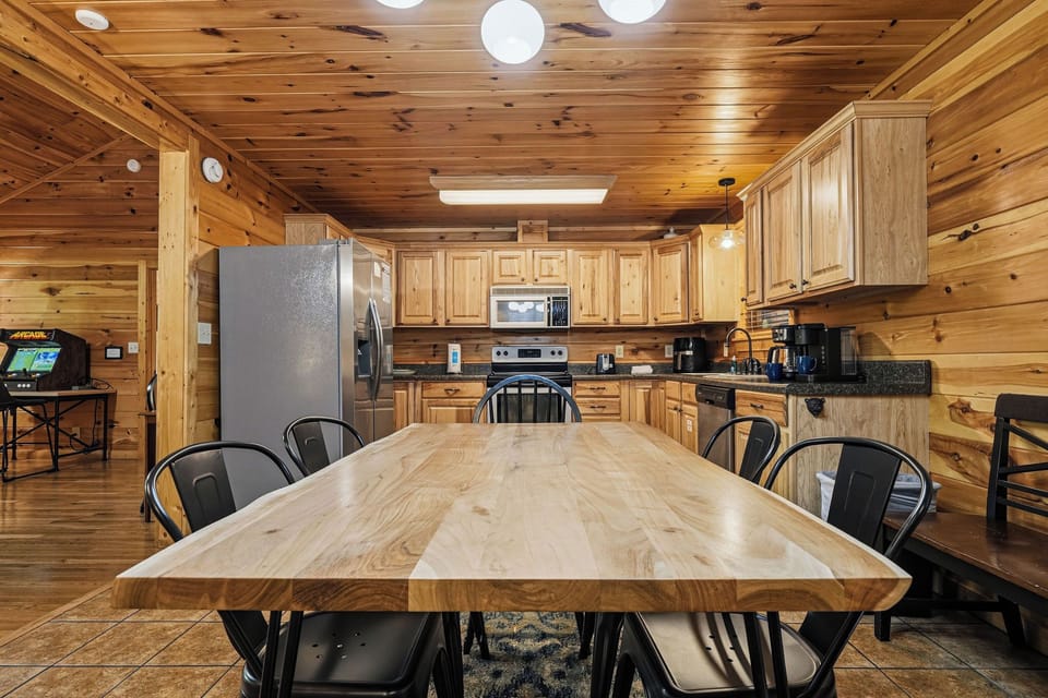Gather around the stunning live-edge wood table in your fully equipped cabin kitchen, where warm timber walls and modern appliances create the perfect space for memorable meals together.