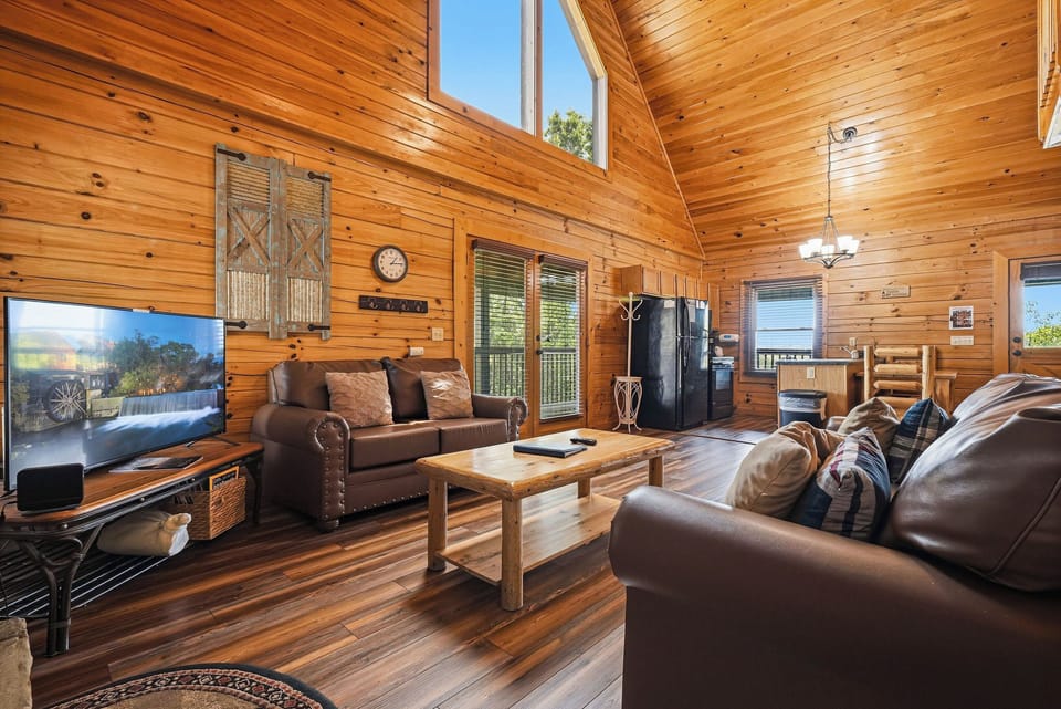 Sink into plush leather sofas beneath soaring wood ceilings. Natural light floods through tall windows while you enjoy your favorite shows on the big screen. Warm wood surrounds you, creating your cozy mountain retreat.
