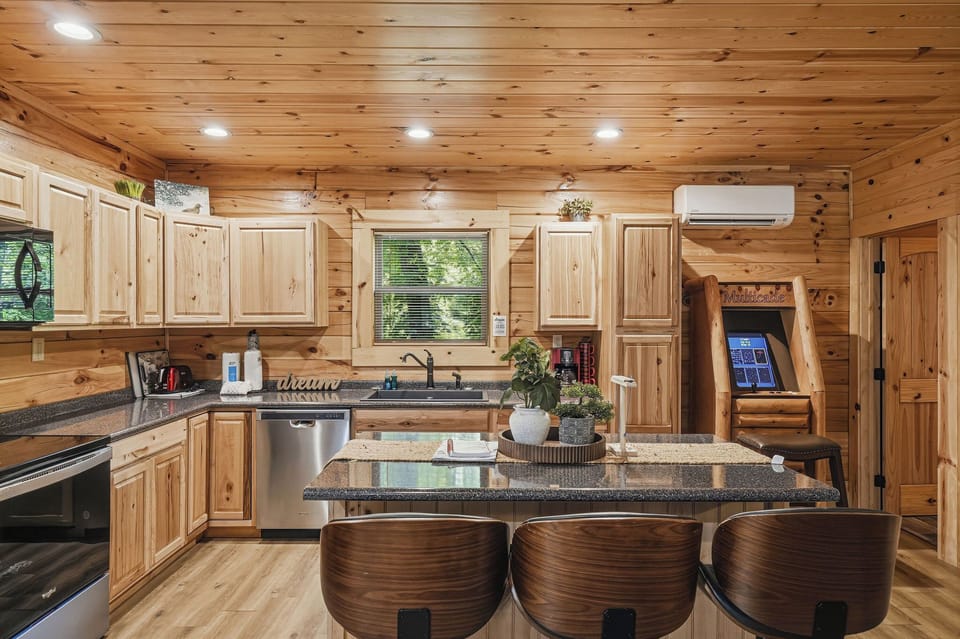 Gather in your spacious cabin kitchen with granite counters, stainless appliances, rustic pine cabinetry, and island seating—perfect for cooking meals together and making memories during your mountain escape.