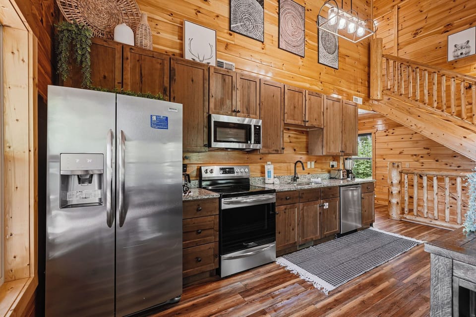Your cabin kitchen features granite counters, modern appliances, and rustic wood cabinetry that perfectly blend comfort and mountain charm.