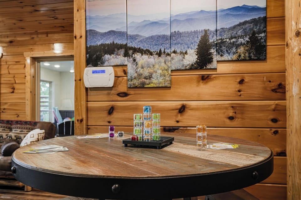 Gather around this rustic table for game nights or morning coffee, with mountain views and cozy wood walls framing your cabin escape.