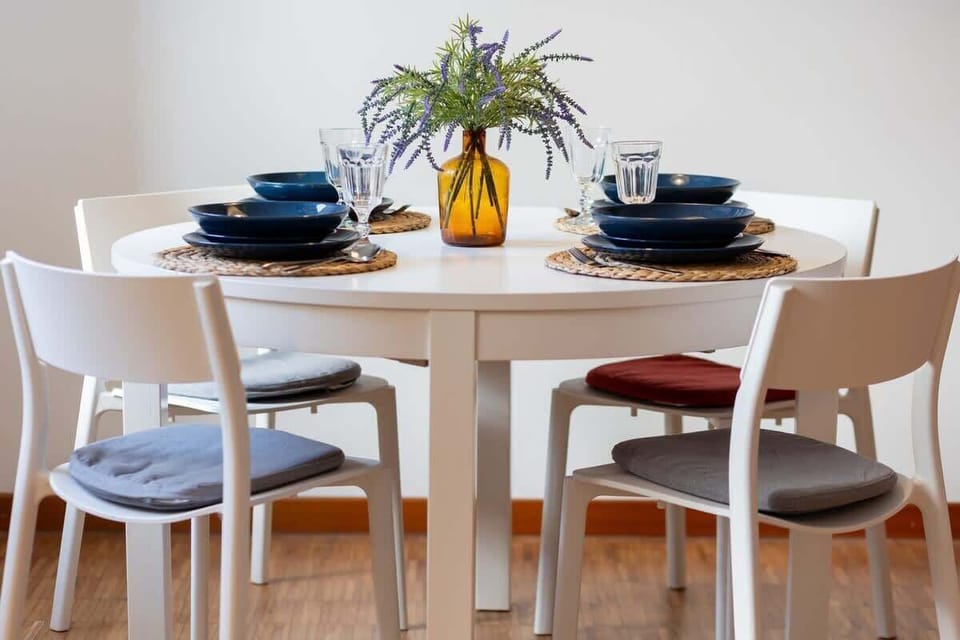 A dining table set with blue plates, a matching teapot, and a small floral centerpiece.

