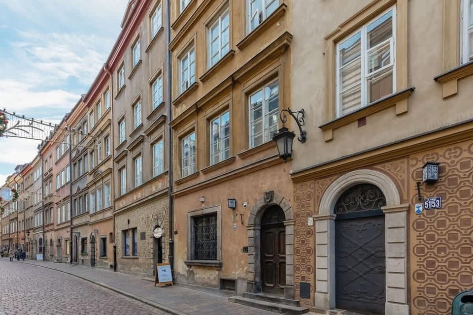 An exterior shot of a historic European street lined with rustic buildings and cobblestone paving.

