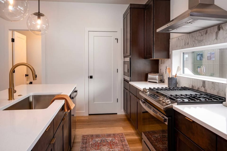 With its modern lighting, windows, quartz countertops, and stunning backsplash, the kitchen makes preparing dinner a truly enjoyable experience.