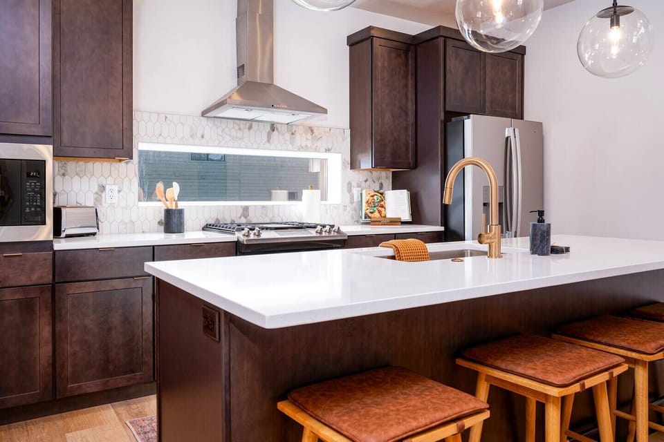 The gourmet kitchen features an island with seating for four and is equipped with brand-new stainless steel appliances, including a microwave, gas stove, and spacious refrigerator.