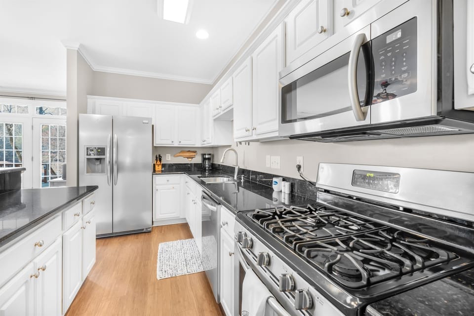 Fully stocked kitchen with a gas grill and stainless steel appliances.