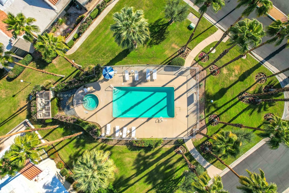 Aerial view of resort-style pool, spa, and lush palm-lined grounds