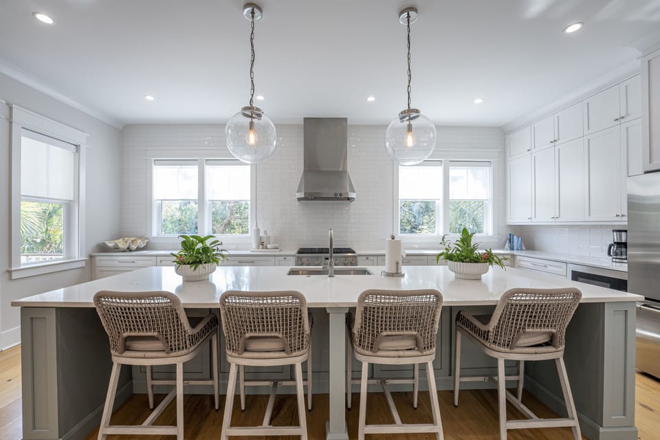 Four counter stools at the large kitchen island. Large open window letting in sunlight.