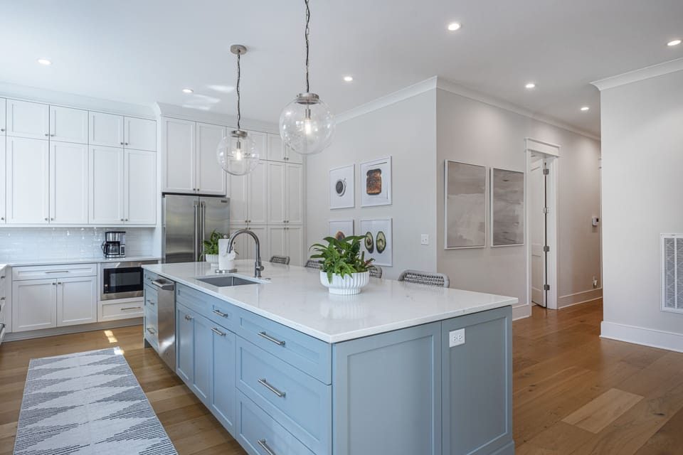 Kitchen island with grey blue cabinets and white counter tops.