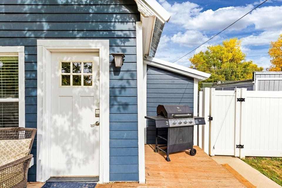 Fenced outdoor patio with barbecue grill and relaxing seating area.