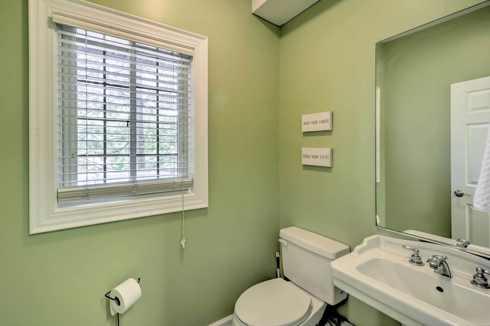 A cheerful half bath with sage green walls and natural light peeking through the blinds at Lillys Mountain Escape.