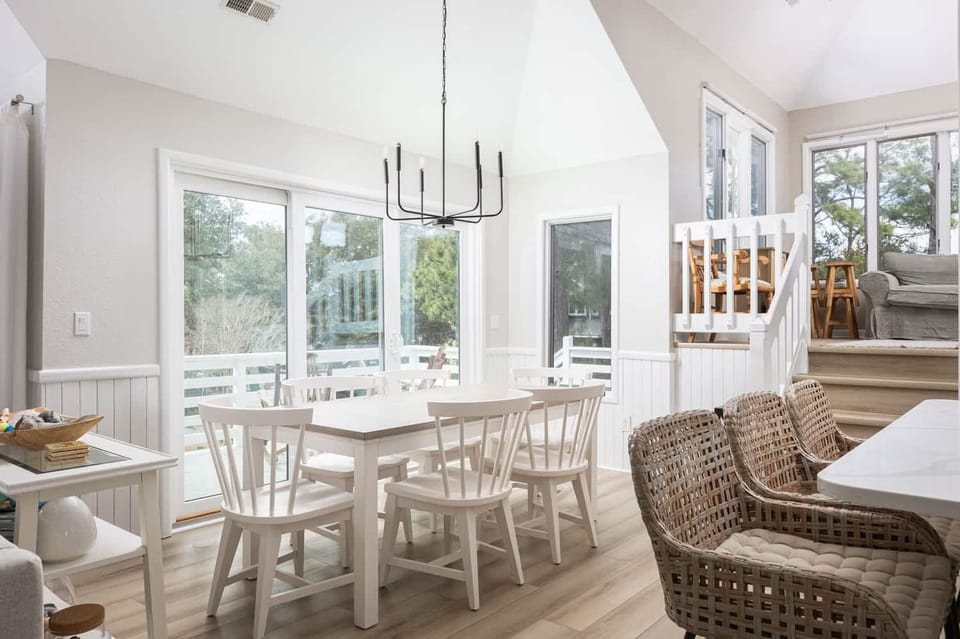 Dining area with seating for 6 and sliding doors that offer a scenic view of the surrounding trees and deck
