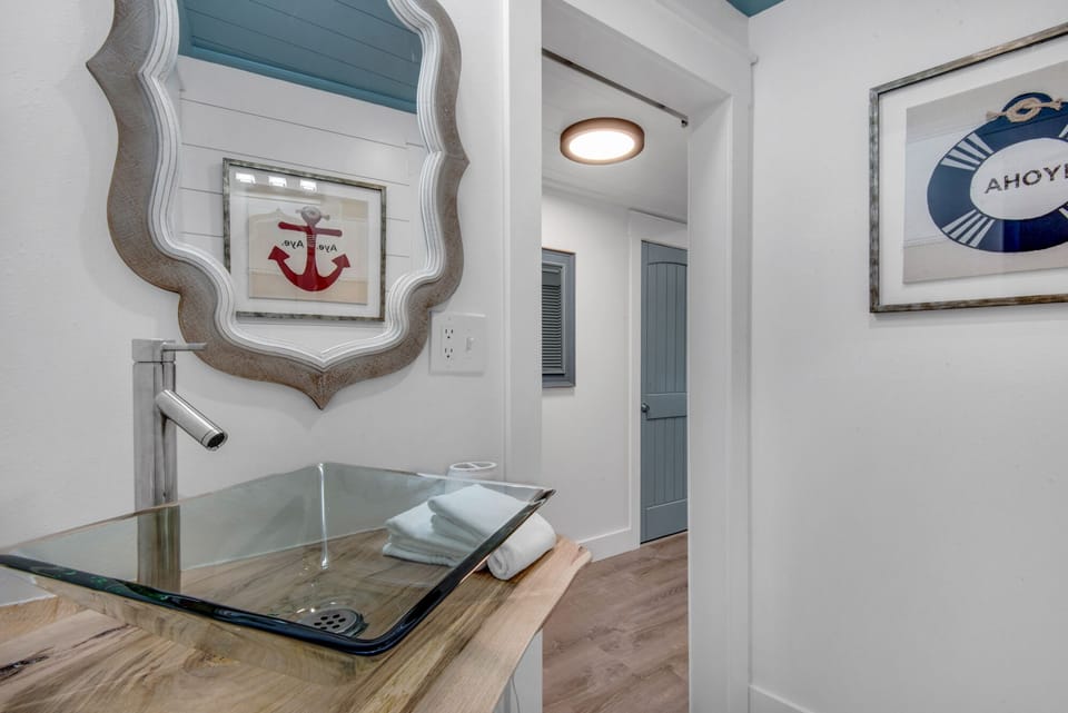 Refresh in your beautifully appointed nautical-themed bathroom, featuring a stunning glass vessel sink and coastal décor that brings seaside charm to your daily routine.