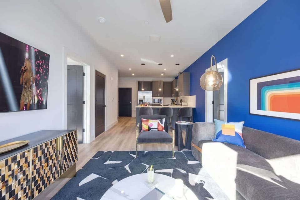 Bright open living space featuring a smart flat-screen TV, designer furnishings throughout, and access to a private patio.