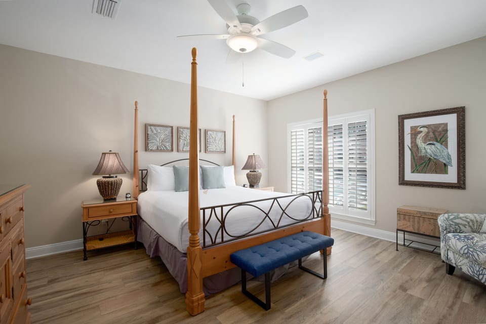 Drift off in your elegant four-poster bed with coastal artwork and gentle ceiling fan creating the perfect retreat.