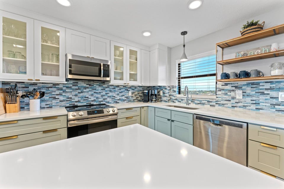 Stylish renovated kitchen with crisp white cabinets and a coastal backsplash.