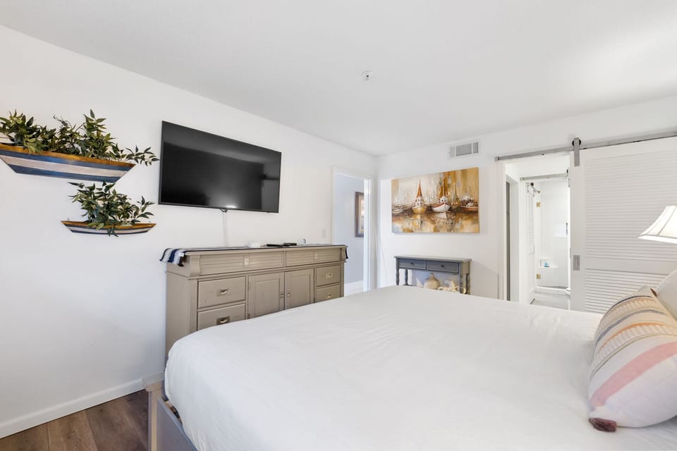 Drift off peacefully in your bright bedroom featuring coastal-inspired decor, wall-mounted TV, and stylish nautical touches.