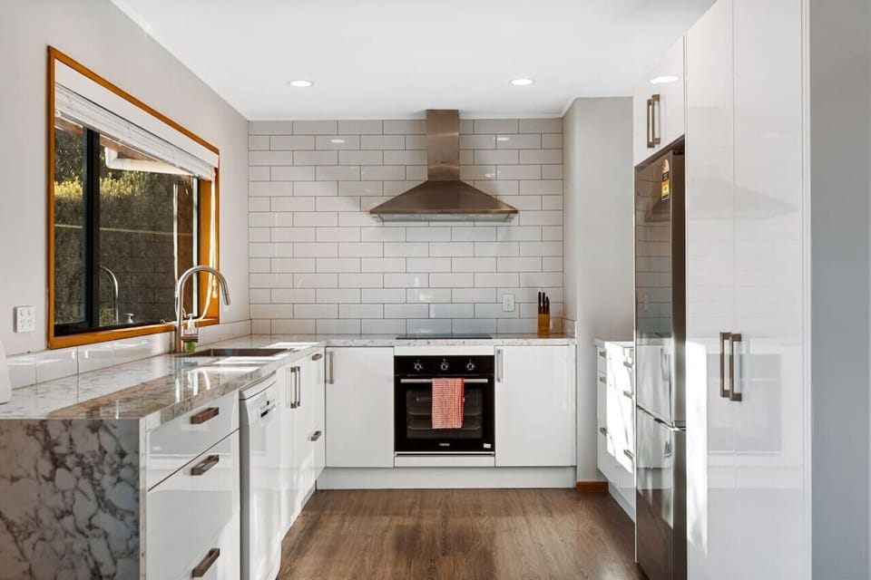 Sleek, fully-equipped kitchen with marble benchtops, subway tile splashback, and quality appliances