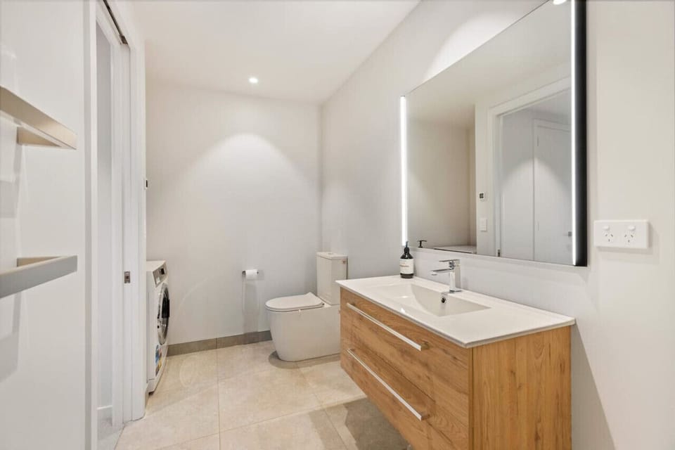 Private ensuite featuring laundry facilities, a basin, shower, heater, and toilet.