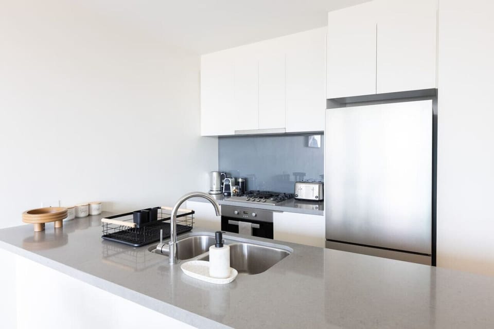 A clean, fully equipped kitchen with stone benchtops, gas cooktop, oven, and stainless steel fridge. Small appliances including a coffee machine and toaster make it easy for guests to cook and settle in comfortably.
