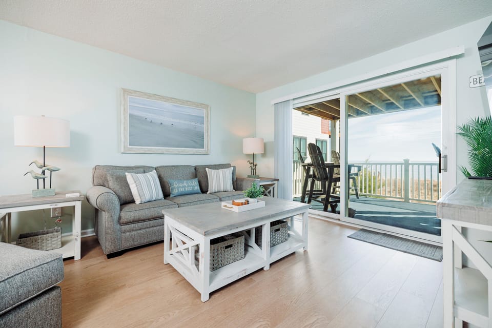 Sink into soft coastal comfort in your bright living room, where ocean breezes flow through open balcony doors to your private deck.