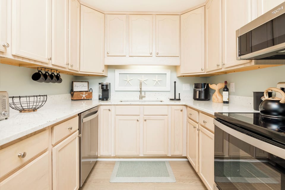 Your fully-equipped kitchen invites culinary adventures with crisp white cabinetry, granite countertops, and thoughtful coastal touches that make cooking feel like home.