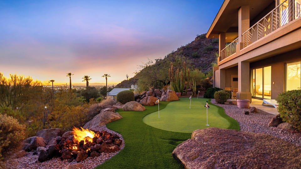 Luxurious backyard with a putting green, fire pit, and city views.