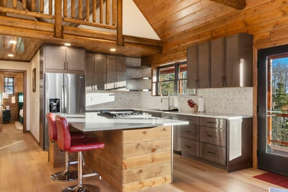 A kitchen bar with 2 bar stools provides a comfortable spot to grab a snack or chat with the chef.