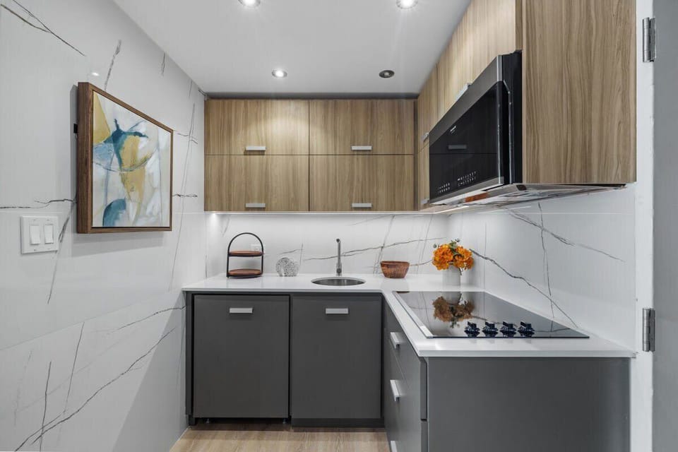 Urban Bliss Flat has a top-notch kitchen! The white stone countertops and wood and gray modern cabinets give it a truly unique look. It has beautiful new cabinetry and it is stocked with cooking pots and pans, has a fridge, microwave, 4-burner stove top, toaster, and coffee maker.