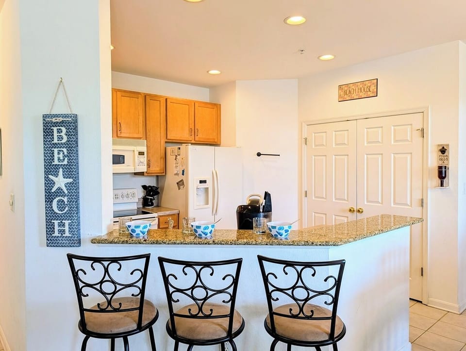 128C October Glory Breakfast Bar Counter - Direct perspective of the kitchen breakfast bar at 128C October Glory featuring three comfortable, ornate counter-height barstools beneath bright recessed ceiling lighting.