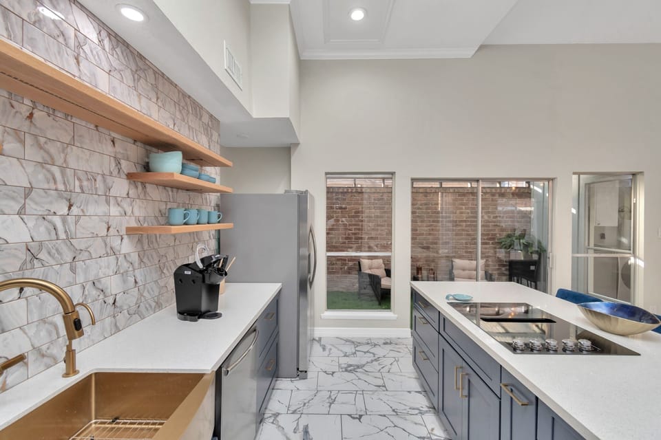 Kitchen area with coffee makers, air fryer, refrigerator with a sunroom 
