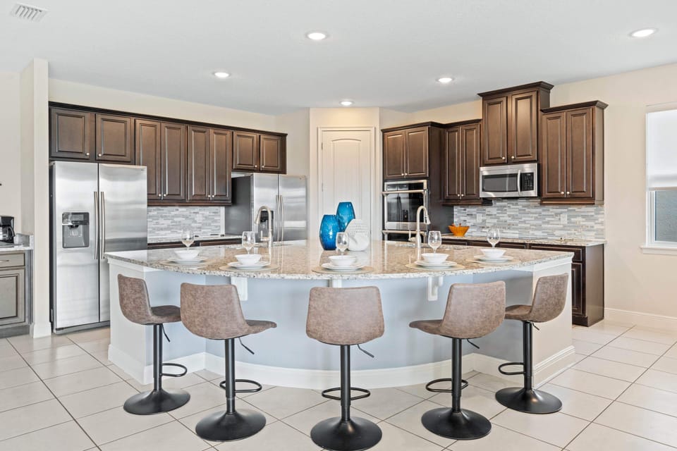 - Dual fridge kitchen with double ovens and curved island bar seating for six  
- Family vacation rental feature ideal for groups traveling to Orlando Disney  
- Plenty of cooking space and modern design create easy meal preparation time