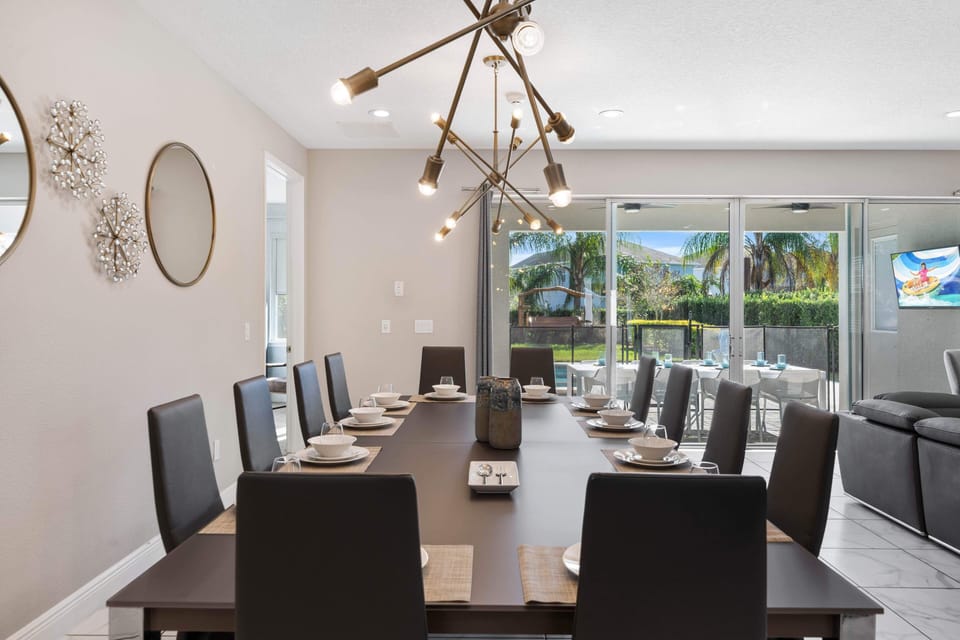- Elegant dining room with modern chandelier lighting  
- Spacious table seating for family dinners and group events  
- Glass doors open to patio with poolside dining setup