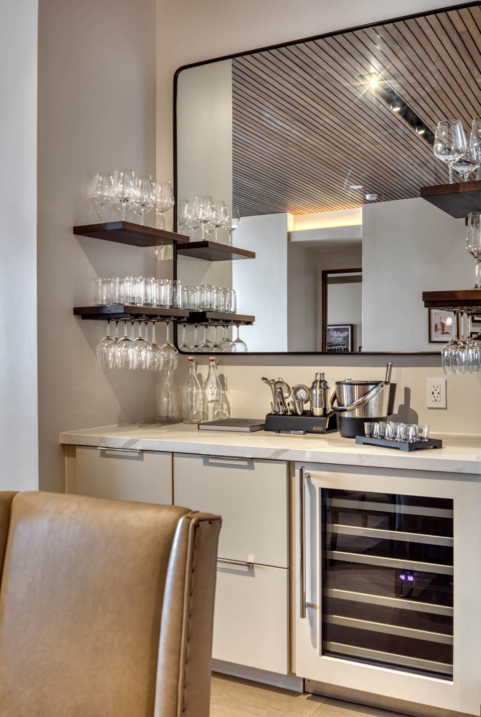 Bar area is stocked with wine and beer glasses, tumblers and wine refrigerator