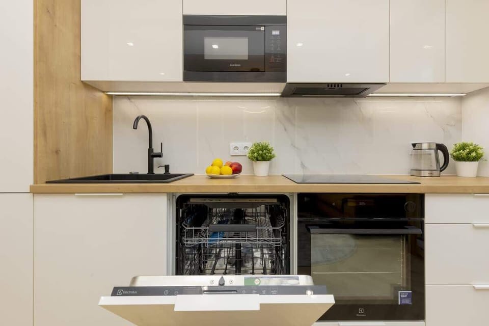 A bright kitchen area featuring a built-in oven and a large sink, seamlessly integrated with the rest of the room for functionality and style.